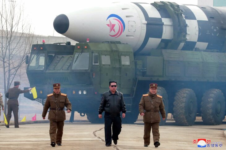 Soldiers with Kim Jong Un walking in front of a war tank 