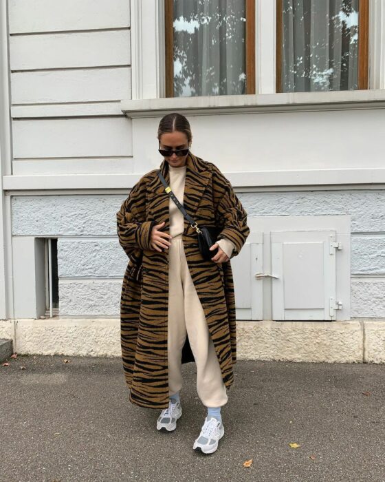 Foto de una chica usando una gabardina furry de animal print usando un coordinado deportivo 