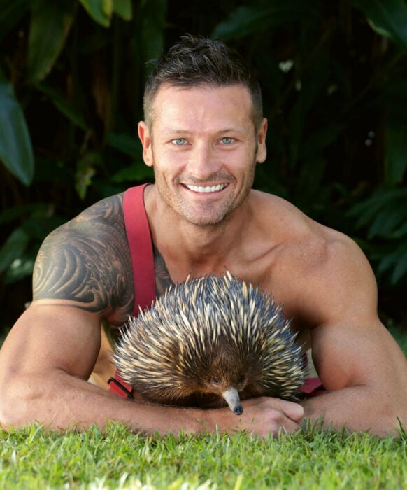 firefighter posing for charity calendar with a porcupine in his arms