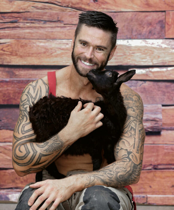 firefighter posing for charity calendar with a sheep