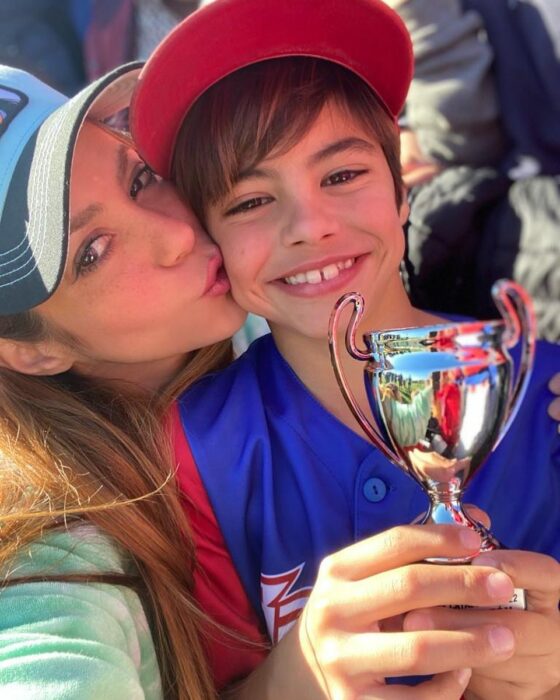 Slefie of Shakira hugging and kissing her son Milan on the cheek with a drink after winning a baseball game 