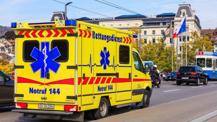 ambulancia de suiza color amarillo con azul estacionada en la calle