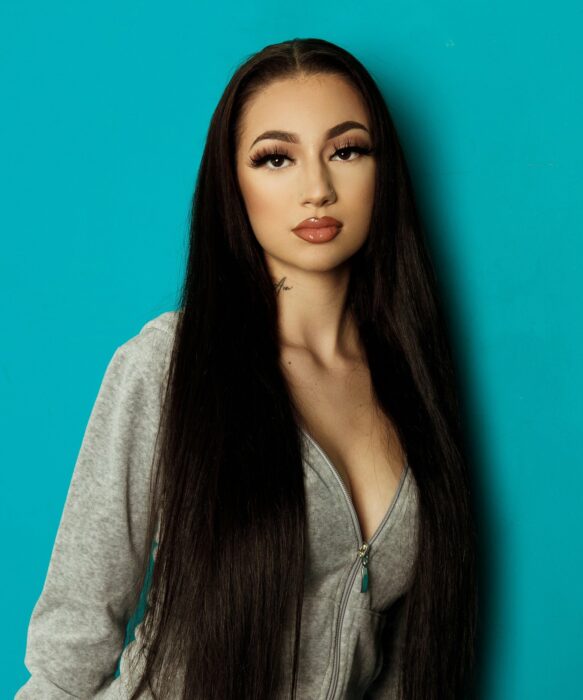 Bhad Bhabie con sudadera gris fondo turquesa