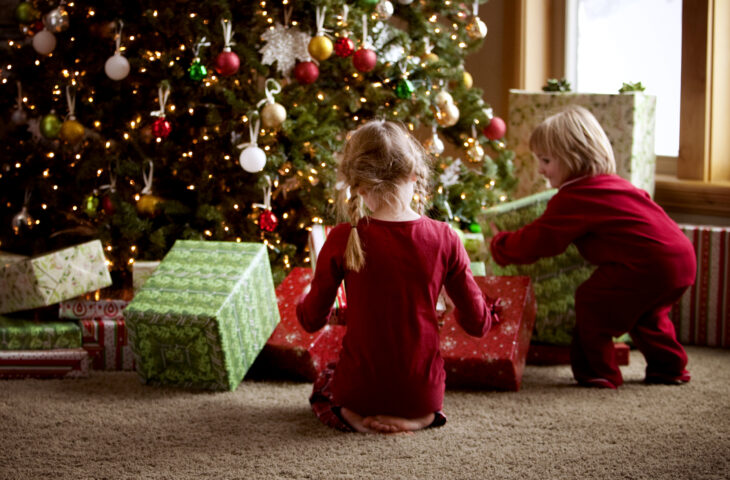 2 niños abriendo regalos en el arbol de navidad