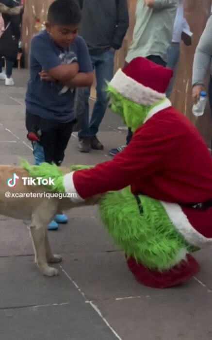 Man dressed as the grinch reacts annoyed with a child