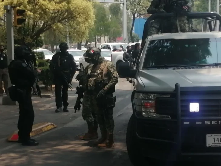 soldiers and policemen on a street, next to a white truck