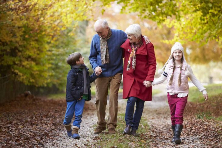 Abuelos caminando con niños entre árboles