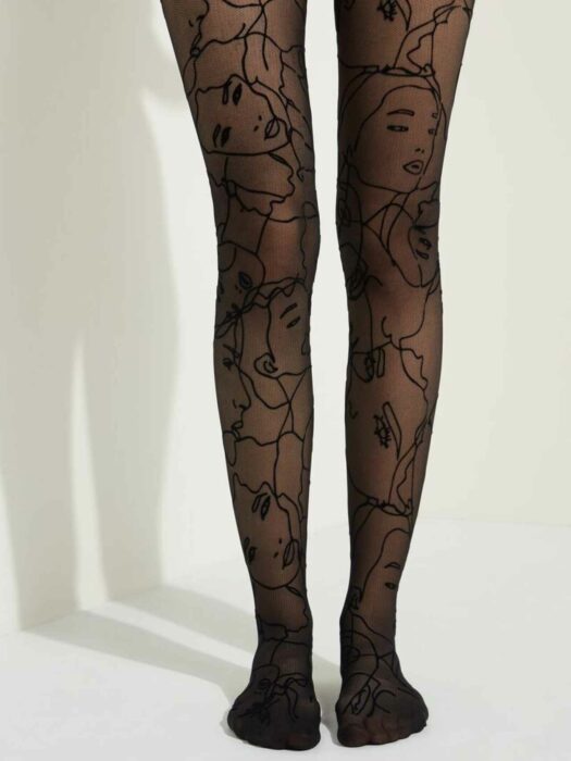 Legs of a woman in a black skirt and black stockings with a print of faces or faces