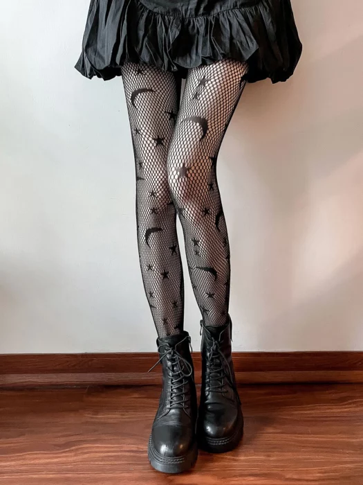 Legs of a woman in a black skirt and black stockings with a pattern of moons and stars