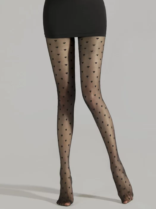 Legs of a woman in a black skirt and black stockings with a pattern of hearts