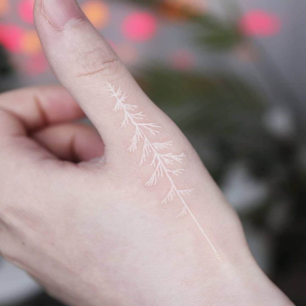 mano de persona con tatuaje de rama de árbol en color blanco