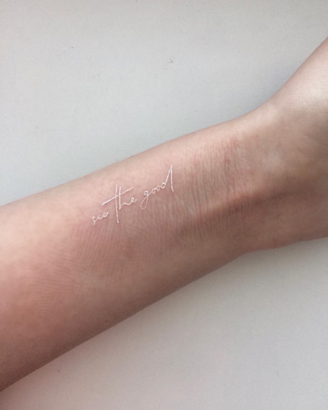 brazo de mujer con frase tatuada color blanco