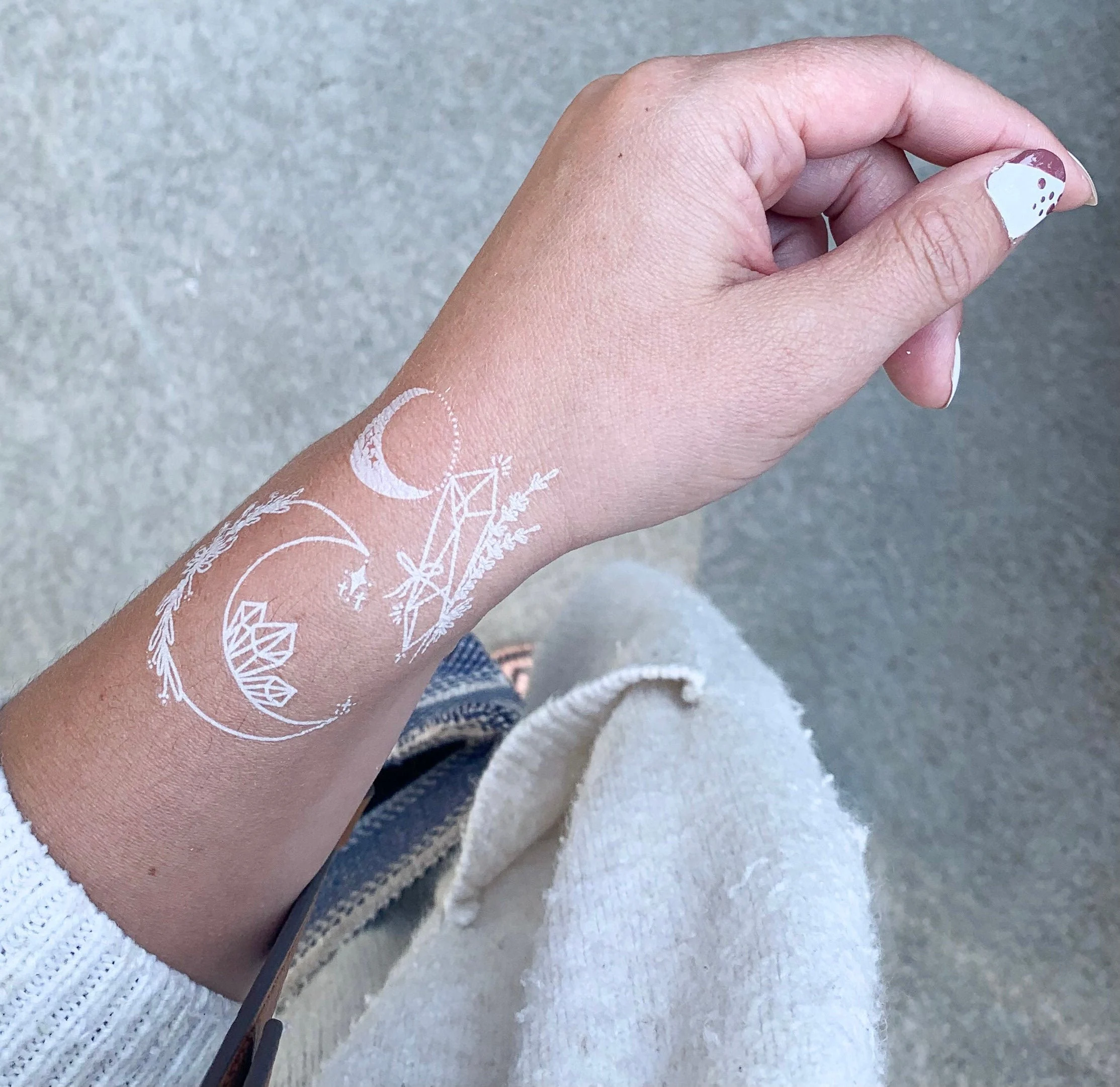mano de mujer con tatuaje blanco en forma de luna