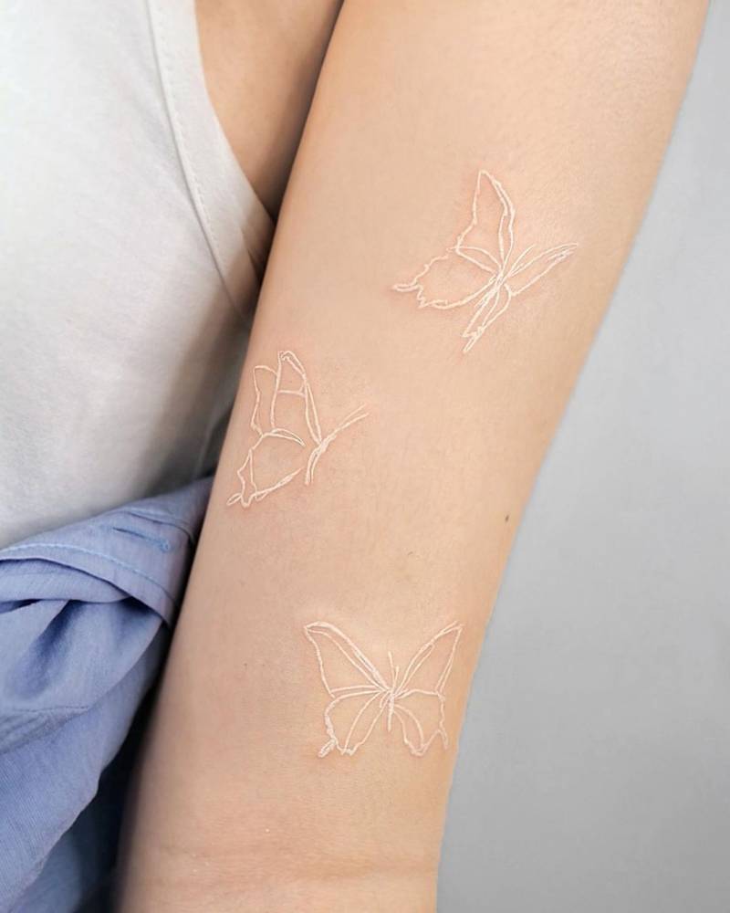 brazo de mujer con tatuajes de mariposas en color blanco