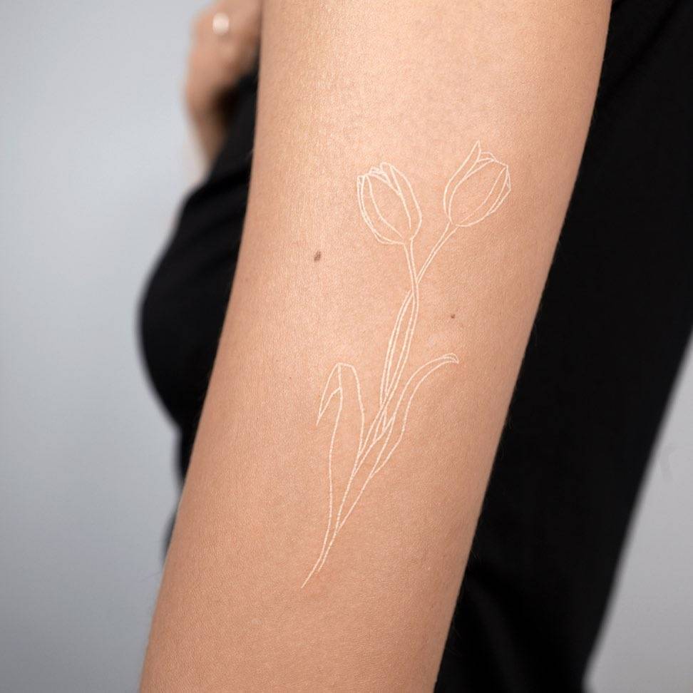 brazo de mujer con tatuaje blanco de tulipán