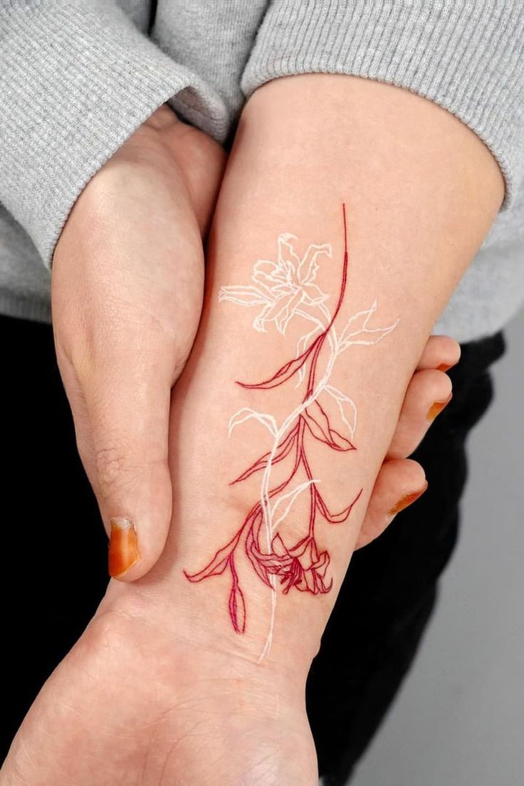 brazo de mujer con tatuajes en forma de flores en colores blanco y rojo