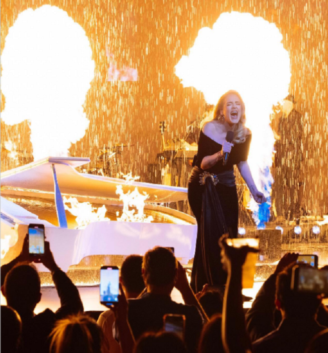 la cantante Adele en su concierto en las Vegas Nevada el escenario simula estar en llamas mientras cae la lluvia ella esta interpretando una de sus canciones con su potente voz