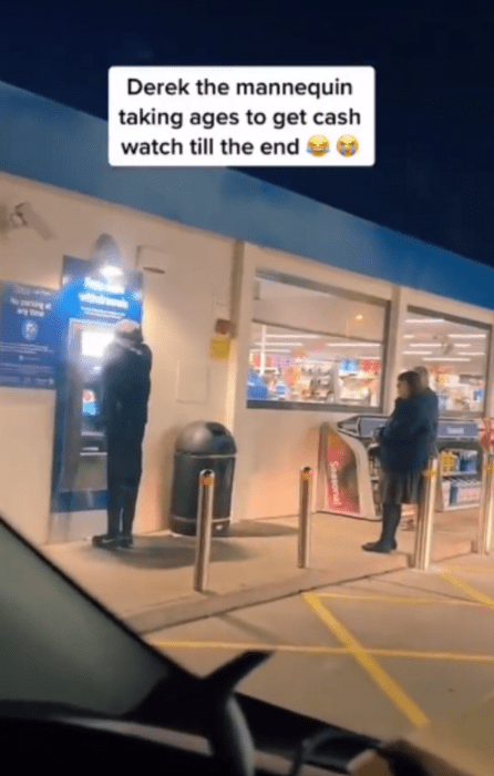 people lined up at an ATM outside a store in the United States a mannequin is placed near the ATM as if performing an operation