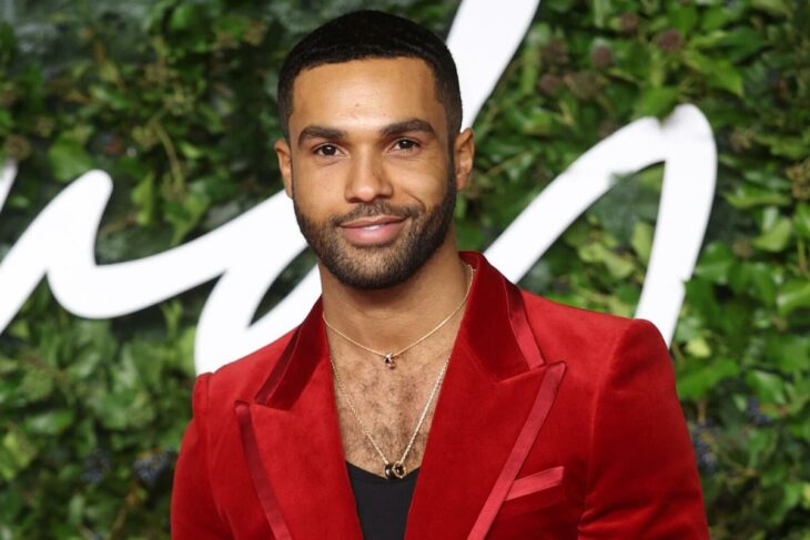 Lucien Laviscount posa con un saco rojo y playera negra en un evento