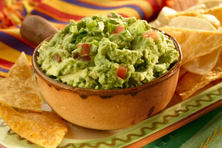 el típico guacamole mexicano servido en una bandeja de barro café 