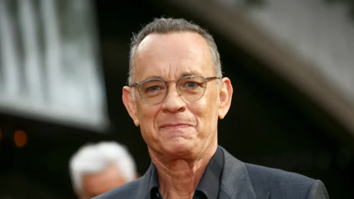 imagen del rostro de Tom Hanks trae lentes transparentes y se aprecia sumamente delgado porta un saco gris con una camisa negra