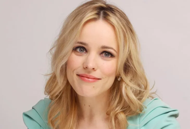 Rachel McAdams tiene el cabello suelto y rubio un maquillaje muy natural esta haciendo un gesto con una ligera sonrisa lleva un vestido verde pastel