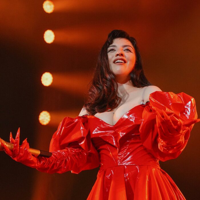 Mon Laferte en concierto con vestido rojo
