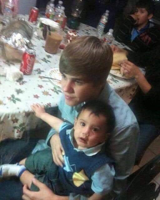 Justin Bieber sentado cargando un bebé de la familia de Selena
