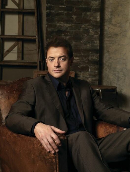 Brendan Fraser sentado en un sofá con un traje oscuro