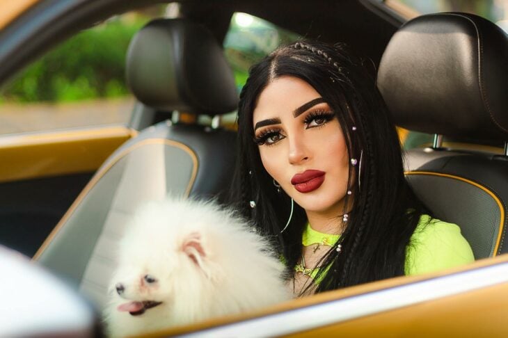fotografía de la cantante Bellakath con un perro blando en sus piernas dentro de un automóvil 