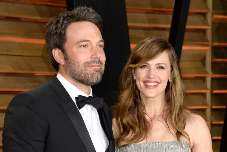 Ben Affleck y Jennifer Garner juntos en una alfombra roja cuando eran esposos llevan trajes de gala Jennifer sonríe a la cámara trae el cabello suelto peinado con ondas y maquillaje discreto el lleva un esmoquin negro 