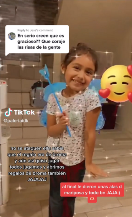 niña sonriendo en una imagen de TikTok lleva una barita mágica de juego y unas supuestas alas de mariposa azules esta sonriendo feliz