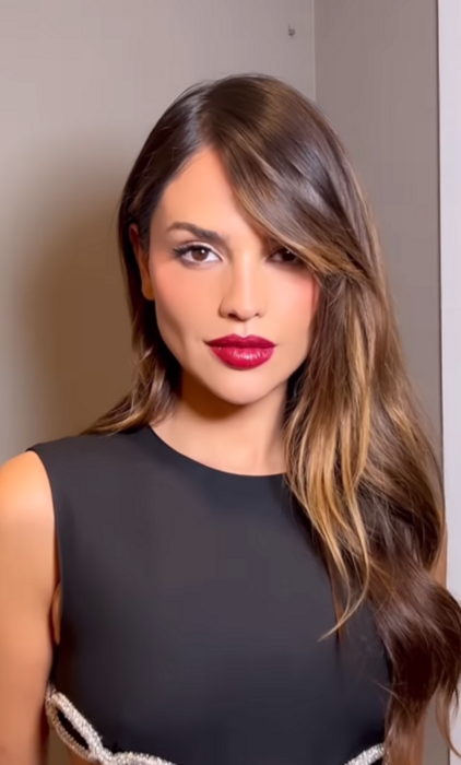 Eiza González posa en una imagen de Instagram lleva el cabello suelto peinado en ondas un maquillaje marcado con labios rojos y un vestido negro de Prada
