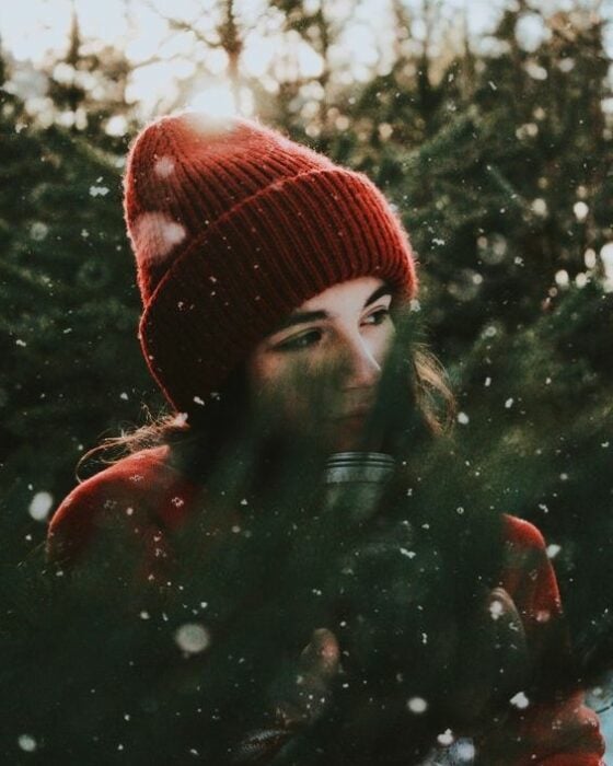 Chica posando entre ramas de pino navideño