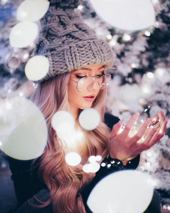 Chica tomando las luces navideñas en sus manos