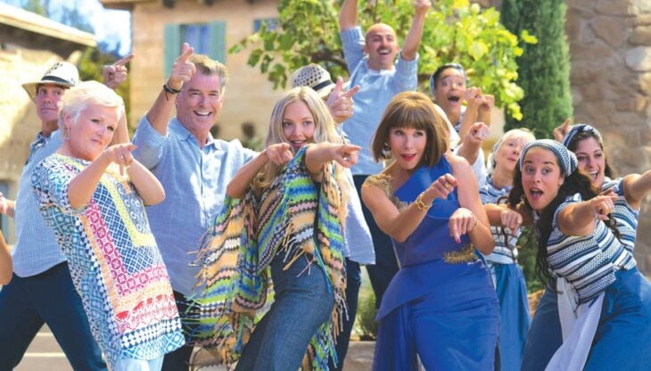 fotografía que muestra una escena de la cinta Mamma Mia! de actores vestidos de azul señalando hacía la cámara 