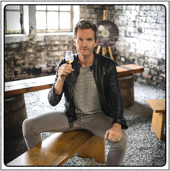 fotografía del actor Neil Patrick Harris sentado con una copa de vino en la mano