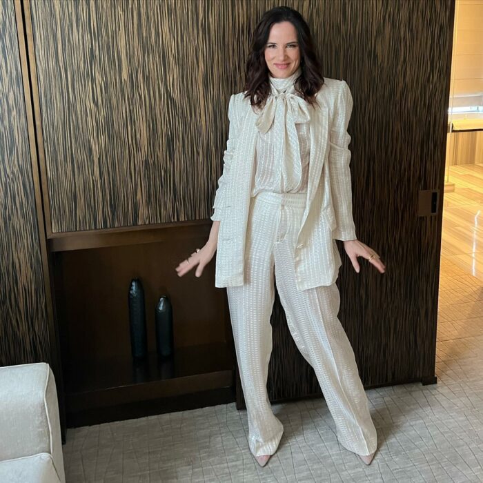 actriz Juliette Lewis posando con un conjunto blanco frente a una sala 