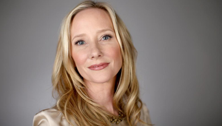 imagen de Anne Heche lleva el cabello largo y rubio peinado en ondas esta haciendo una mueca de sonrisa lleva un maquillaje natural 