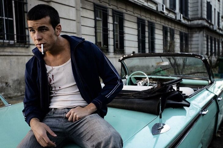 Mario Casas sobre un carro color verde menta con un cigarro en la boca interpretando a un personaje de adolescente rebelde 