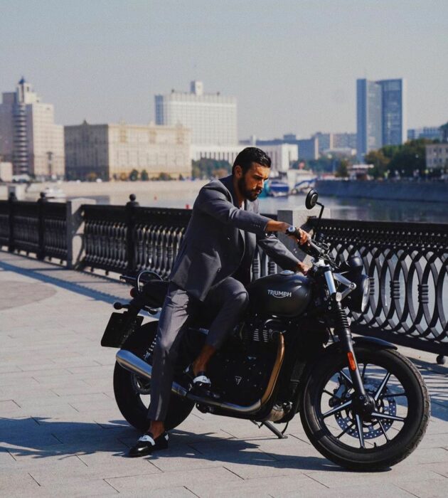 fotografía de Mario Casas montado en una moto frente a un lago en una ciudad 