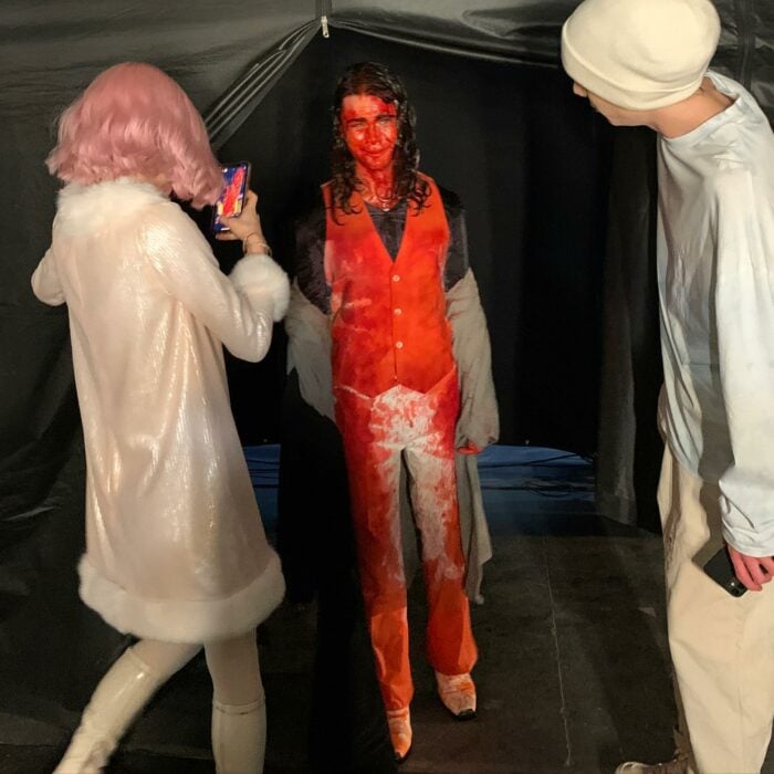 imagen que muestra un detrás de cámaras de la serie de Merlina en la que un actor está lleno de pintura en color rojo 