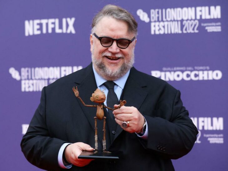 Guillermo del Toro posando en el Festival del Cine de Londres 2022 con una figura de Pinocho de madera 