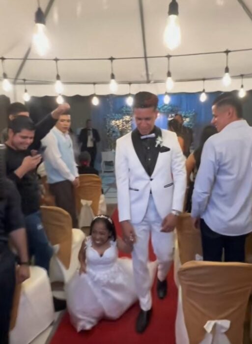 Fotografía de unos recién casados saliendo de la ceremonia religiosa mientras sus invitados los ven 