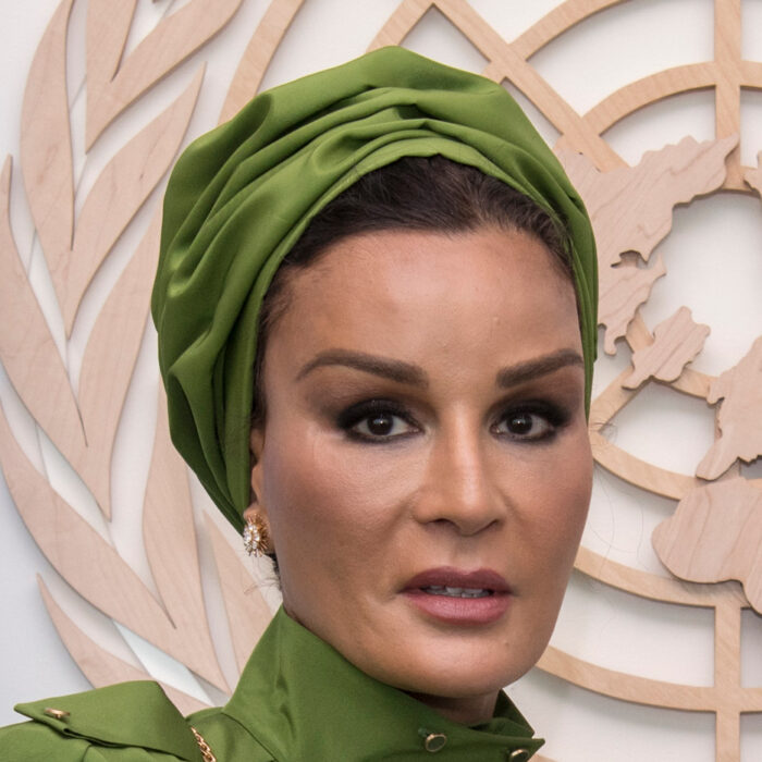 una de las mujeres más distinguidas y elegantes de Catar, la exjequesa Moza bin Nasser al-Missned en una imagen de su rostro lleva un turbante verde combinado con su blusa verde tras de ella se ve el escudo de la Unicef 