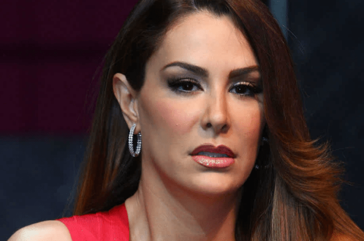 la actriz y cantante Ninel Conde en una imagen donde le tomaron el rsotro en priemer plano lleva unas argollas de diamantes en los oídos maquillaje pronunciado el cabello largo y suelto lacio y una prenda de vestir de color rojo