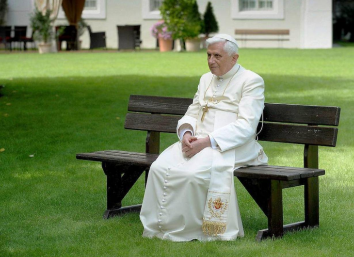 El papa emérito Benedicto XVI sentado en una banca en los jardines de su hogar en el Vaticano viste ornamento blanco