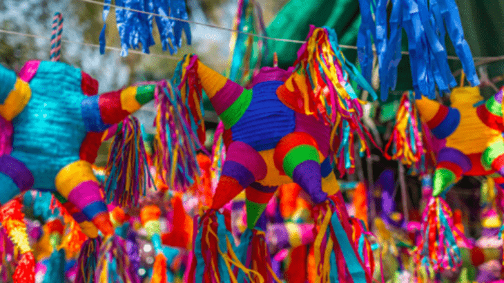 imagen de montones de piñatas de colores juntas con forma de estrellas hechas en papel crepé y colgadas del techo