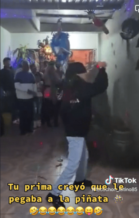 imagen que muestra el momento en que una chica intenta romper una piñata pero quiebra una maceta lleva un pantalón azul de mezclilla y una sudadera negra trae los ojos vendados