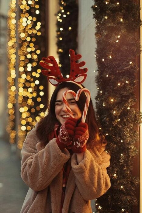 Mujer formando un corazón con bastones de dulce navideños
